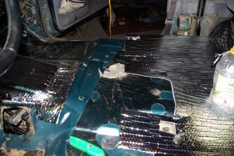 1995 Ford Bronco - Sound deadening insulation being installed on the floor of a vehicle's interior.