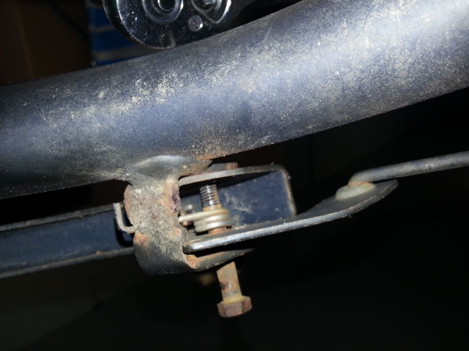 Close-up of a rusty metal bracket with a bolt and spring mechanism