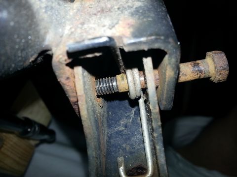 1994 Ford Bronco - This image shows a close-up view of a corroded metal bracket with a bolt and washer, likely a vehicle part.