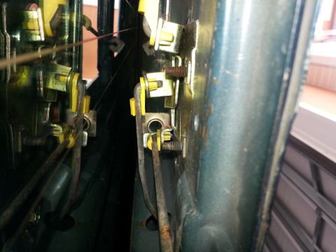 1994 Ford Bronco - Close-up of a vehicle's internal door latch mechanism, showing various rods and yellow plastic components.