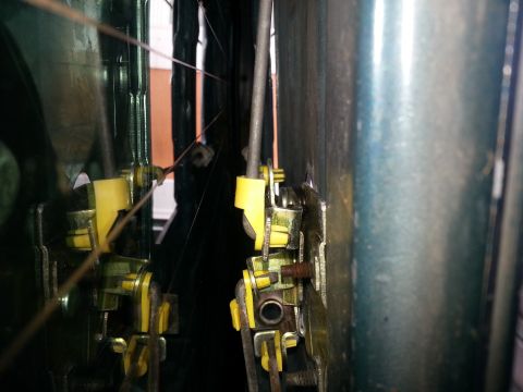 1994 Ford Bronco - Close-up view of a vehicle's internal door latch mechanism, showing yellow plastic parts and metal cables.