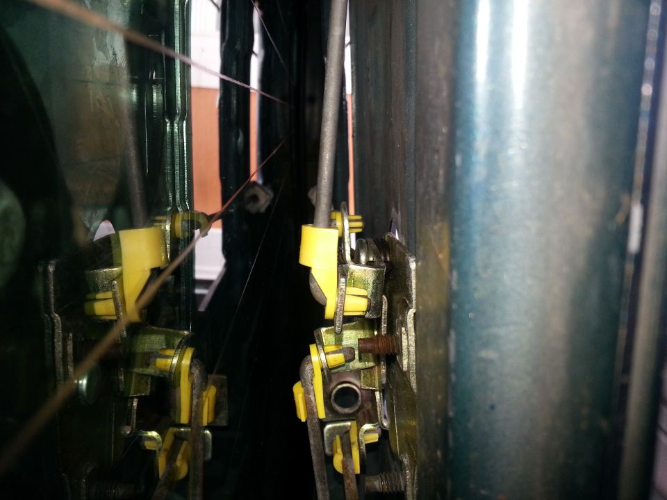 Door latch mechanism with yellow plastic components and metal cables