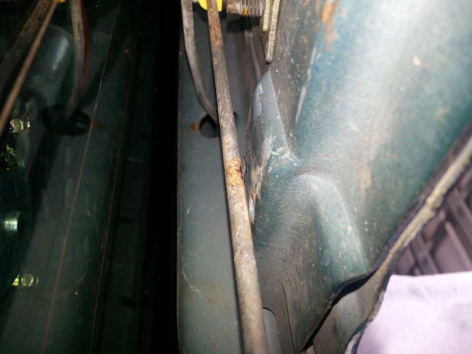Close-up of a car's interior door latch mechanism with visible rust and cables