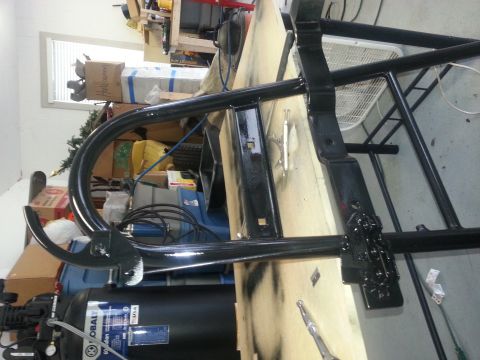 1994 Ford Bronco - A black metal frame part is shown in a workshop setting, with an air compressor visible.