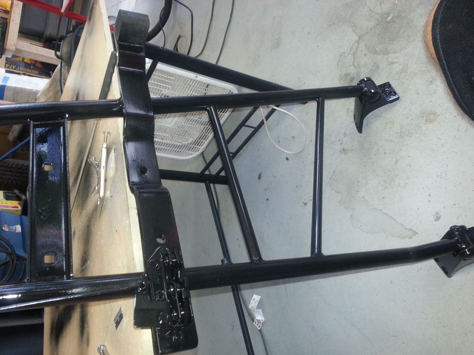black painted frame pieces, possibly for a vehicle chassis, on a workbench