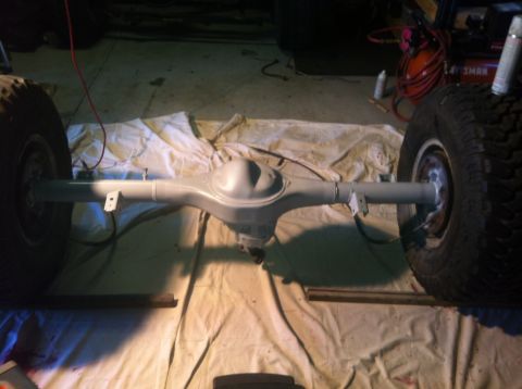 1979 Ford Bronco - A vehicle's rear axle assembly, with tires still attached, is laid out on a drop cloth in a garage.