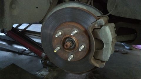 1996 Ford Taurus - Close-up of a vehicle's front brake rotor and caliper, indicating a need for maintenance.