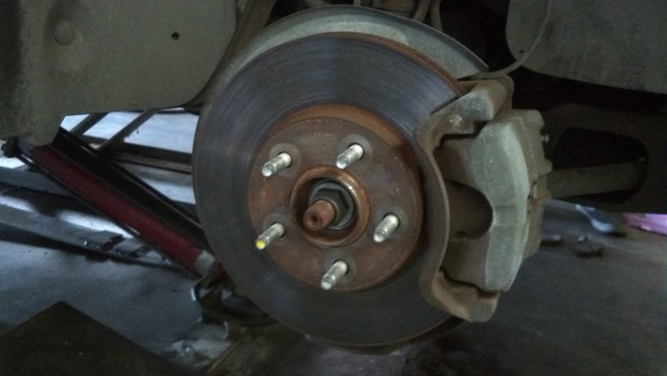 Car brake rotor and caliper assembly, showing wear and rust
