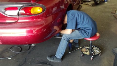 1996 Ford Taurus - Mechanic performs work on the rear of a 1996 Ford Taurus in a garage setting.