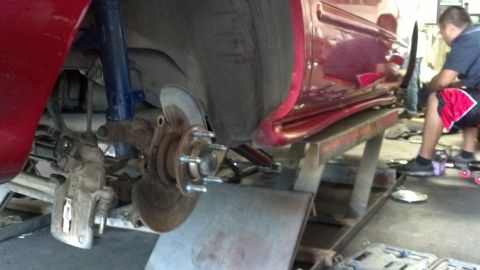 1996 Ford Taurus - Close-up view of a red car's rear wheel assembly, showing the brake rotor and caliper removed for service.