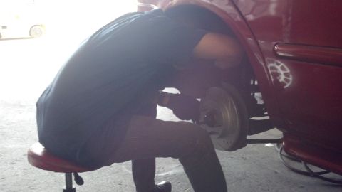 1996 Ford Taurus - Mechanic working on the brake rotor of a red vehicle.