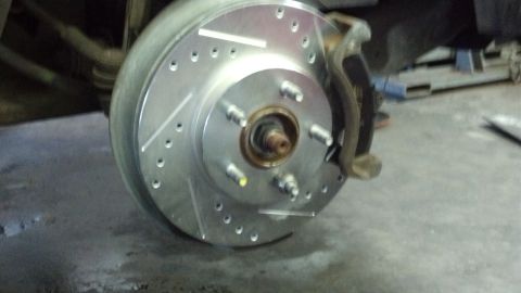 1996 Ford Taurus - Close-up view of a new drilled and slotted brake rotor with pads and caliper installed.