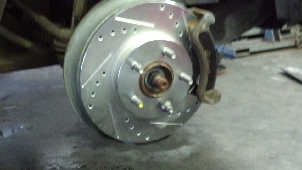 Drilled and slotted brake rotor with new pads and caliper