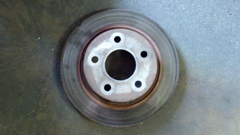 1996 Ford Taurus - A single brake rotor is shown resting on a concrete surface.