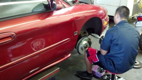 1996 Ford Taurus - Mechanic working on the brake rotor of a red 1996 Ford Taurus.