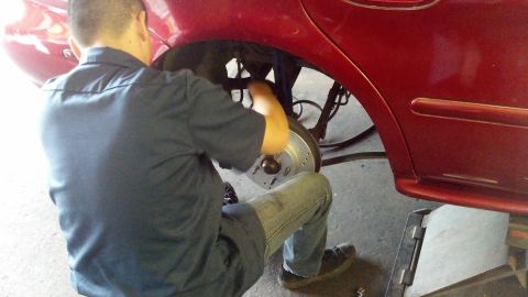 1996 Ford Taurus - Mechanic replacing brake rotor on a red vehicle.
