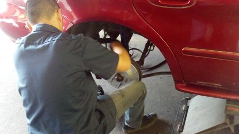 1996 Ford Taurus - A person is working on the brake system of a red vehicle, likely replacing a rotor.