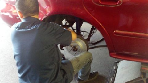 1996 Ford Taurus - Mechanic replaces the brake rotor on a red 1996 Ford Taurus.