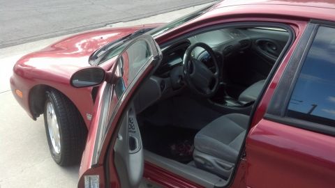 1996 Ford Taurus - Interior view of a red 1996 Ford Taurus, driver's door ajar.