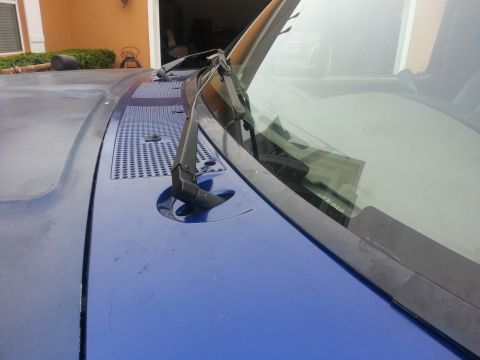 1994 Ford Bronco - Close-up view of the hood and windshield wipers of a blue vehicle.