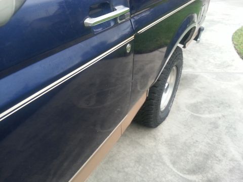1994 Ford Bronco - Side view of a 1994 Ford Bronco, focusing on the door and rear wheel area.