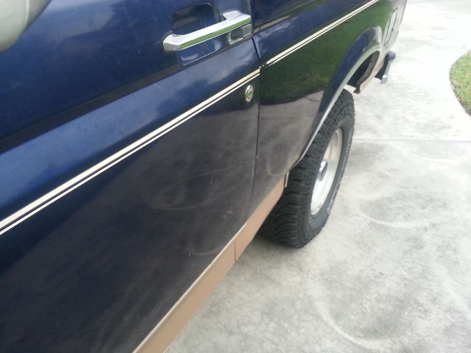 1994 Ford Bronco side view showing door handle, pinstripes, and wheel