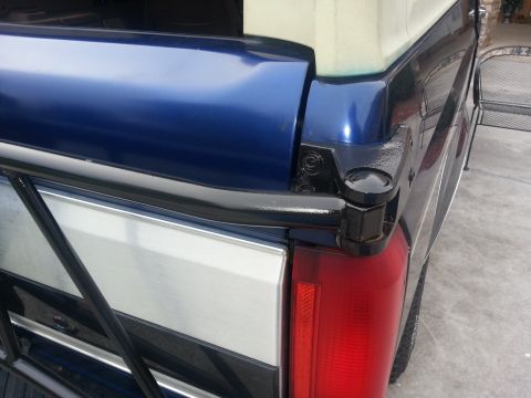 1994 Ford Bronco - Close-up of the rear of a blue Ford Bronco, showing the tailgate and a portion of the roll bar.