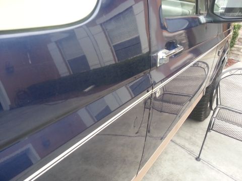 1994 Ford Bronco - Side view of a dark blue 1994 Ford Bronco, showing its door handle and decorative pinstriping.