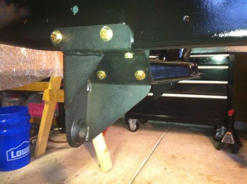 1979 Ford Bronco - Close-up view of a vehicle's undercarriage, showing a bolted metal bracket and supporting wooden blocks.