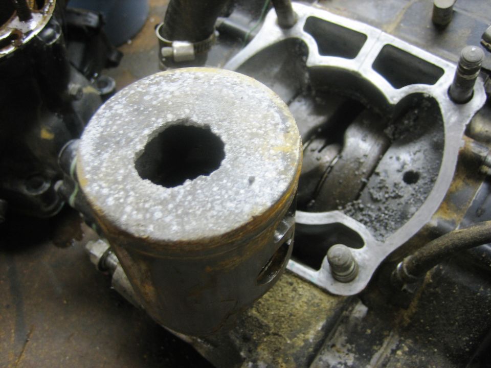 Disassembled engine cylinder and piston with visible wear and debris