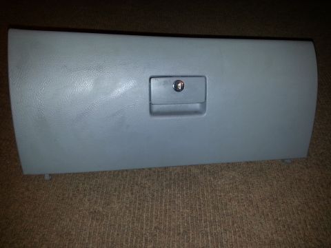 2002 Volkswagen Jetta - A gray plastic glove box door with a lock is shown against a carpeted background.