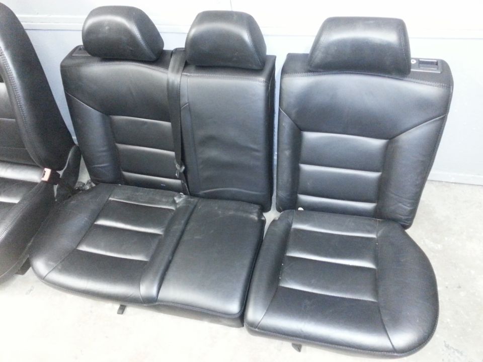 Set of black leather automotive seats with headrests removed from car