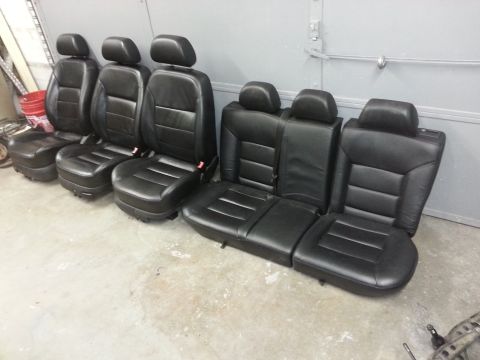 2002 Volkswagen Jetta - A set of black leather car seats, likely from a sedan, are displayed on a concrete floor.