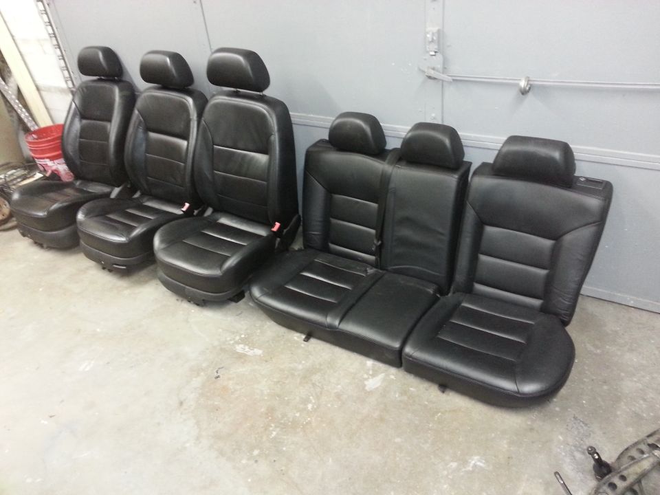 Set of black leather car seats, including front bucket seats and rear bench seats