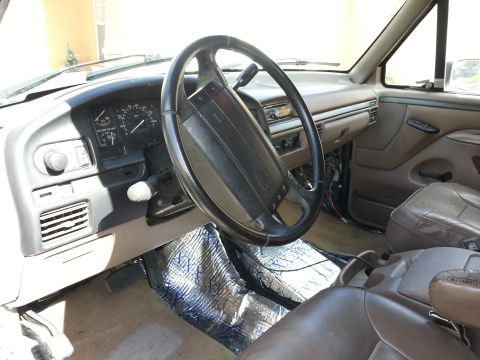1994 Ford Bronco - The interior of a 1992 Ford Bronco shows brown leather seats and a dashboard with sound deadening material on the floor.