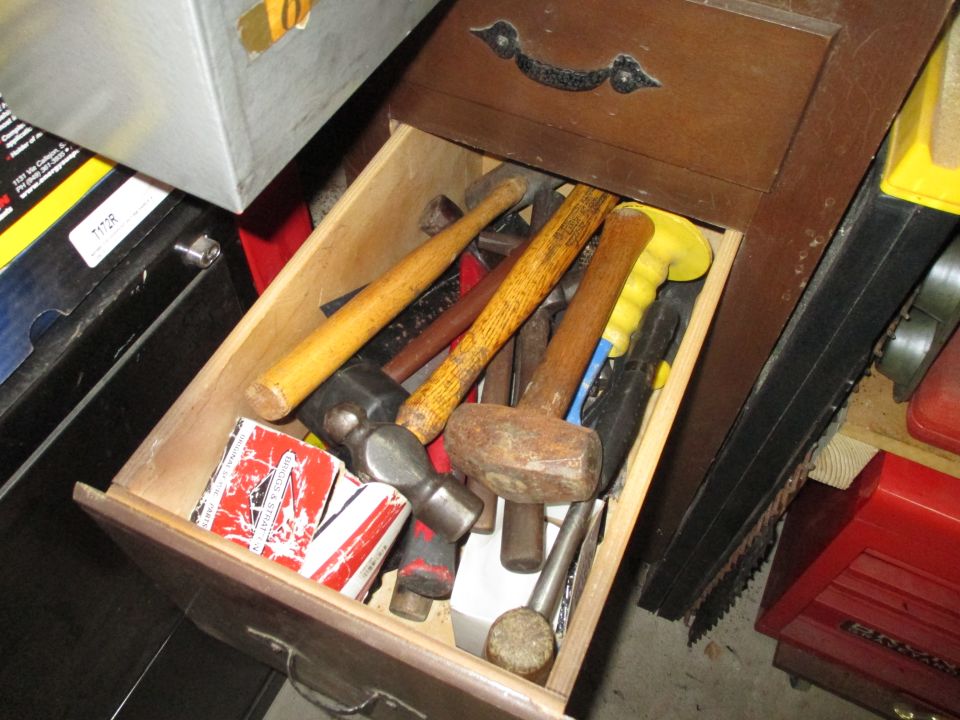 Drawer filled with hammers and tools, including a red and white box