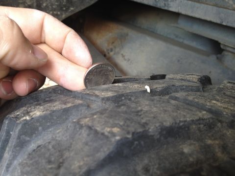 2000 Jeep Wrangler - A quarter is used to measure the tread depth on a tire, indicating wear.