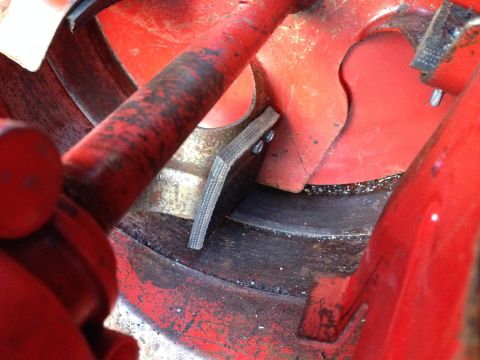 1999 Tomos Targa - A close-up view of a red metal component a ribbed belt secured by two screws.