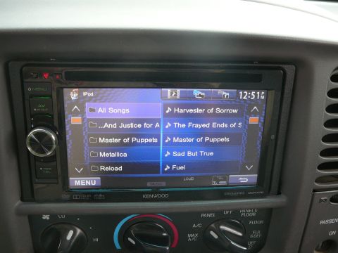 1988 Ford Bronco - Aftermarket car stereo showing iPod interface with song list and clock at 12:51 PM.