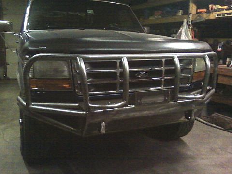 1989 Ford Bronco - Front view of a dark-colored Ford truck a custom metal bumper and grille guard.