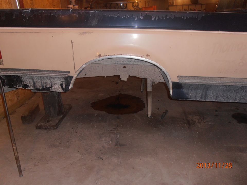 1988 Ford F-250 rear wheel well and bed side, showing rust and dirt. Truck is on jack stands