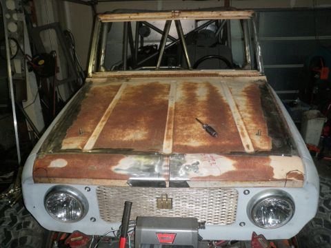1961 International Scout 800 - The front of a 1961 International Scout 800, showing its rusty hood and grille, with a roll cage visible.