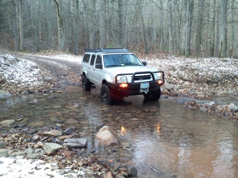 2003 Nissan Frontier - This 2003 Nissan Frontier is navigating a rocky stream bed in a forest with light snow on the ground.