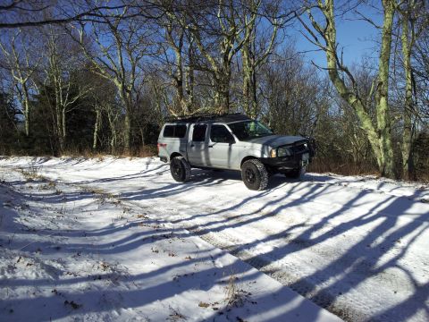 2003 Nissan Frontier - A four-door Nissan Frontier pickup truck is parked on a snow-covered path with trees in the background.