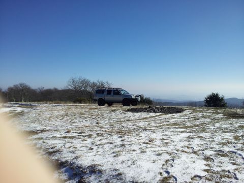 2003 Nissan Frontier - A silver 2003 Nissan Frontier pickup truck is parked on a snowy hillside under a clear blue sky.