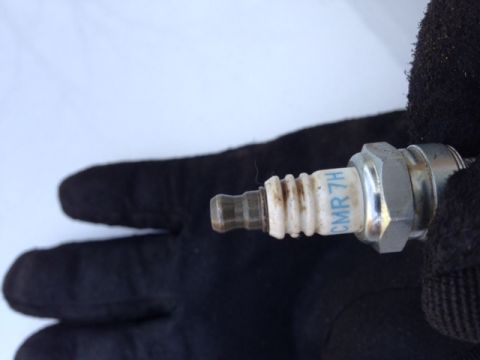 1999 Tomos Targa - A spark plug marked CMR 7H is held by a gloved hand against a white background.