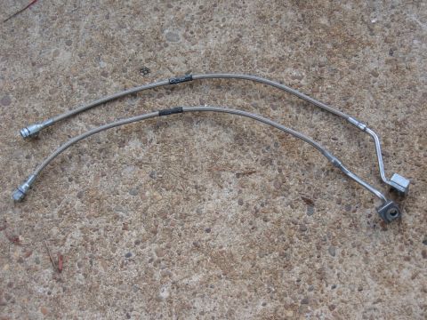 1994 Ford Bronco - Two stainless steel braided brake lines, likely for a vehicle, are shown laid out on a concrete surface.