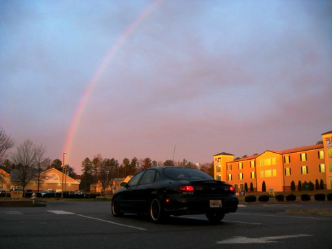 1997 Ford Taurus - A black 1997 Ford Taurus SHO is seen under a vibrant rainbow at dusk.