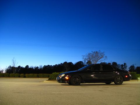 1997 Ford Taurus - Side view of a black 1997 Ford Taurus sedan parked in a lot at dusk.