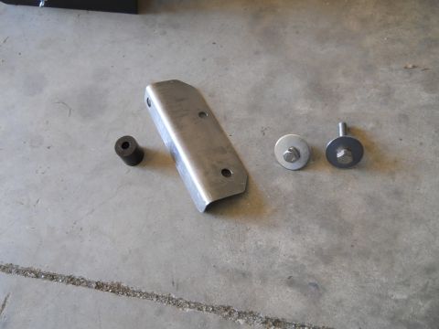 1992 Ford Bronco - Metal bracket and hardware are laid out on a concrete floor.